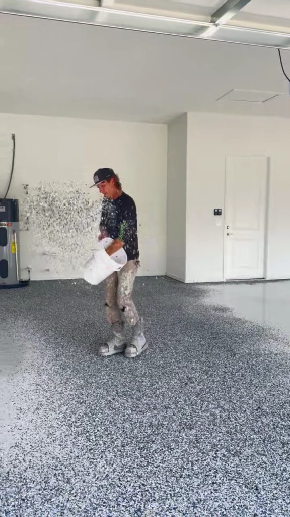 Installer broadcasting flake into a garage floor base coat