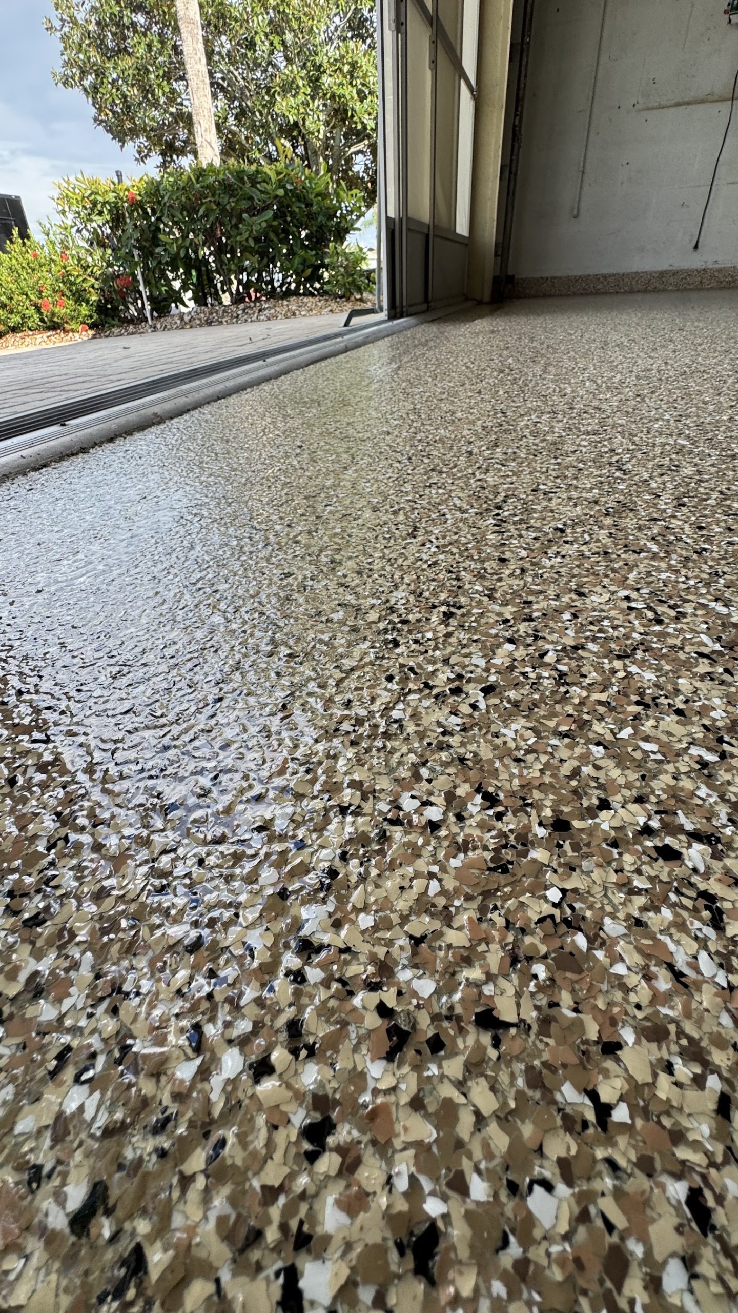 Tan and black flake epoxy floor coating transitioning to a covered lanai